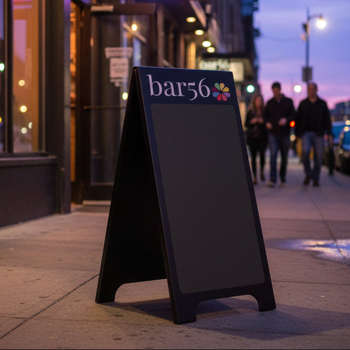 Black a-frame sign with 'bar56' logo on twilight street