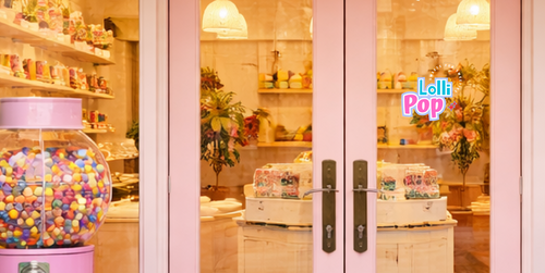 Pink glass door with colorful gumball machine and 'Lollipop' sign on the door