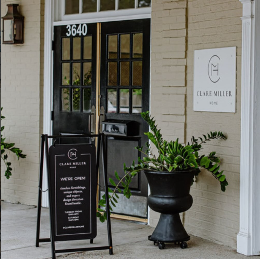 Front entrance of a building with a sign and open door, featuring the brand 'Clare Miller'.