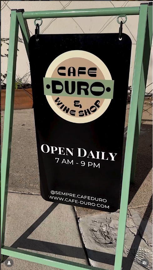 Outdoor sign for Cafe Duro and Wine Shop with business hours displayed.