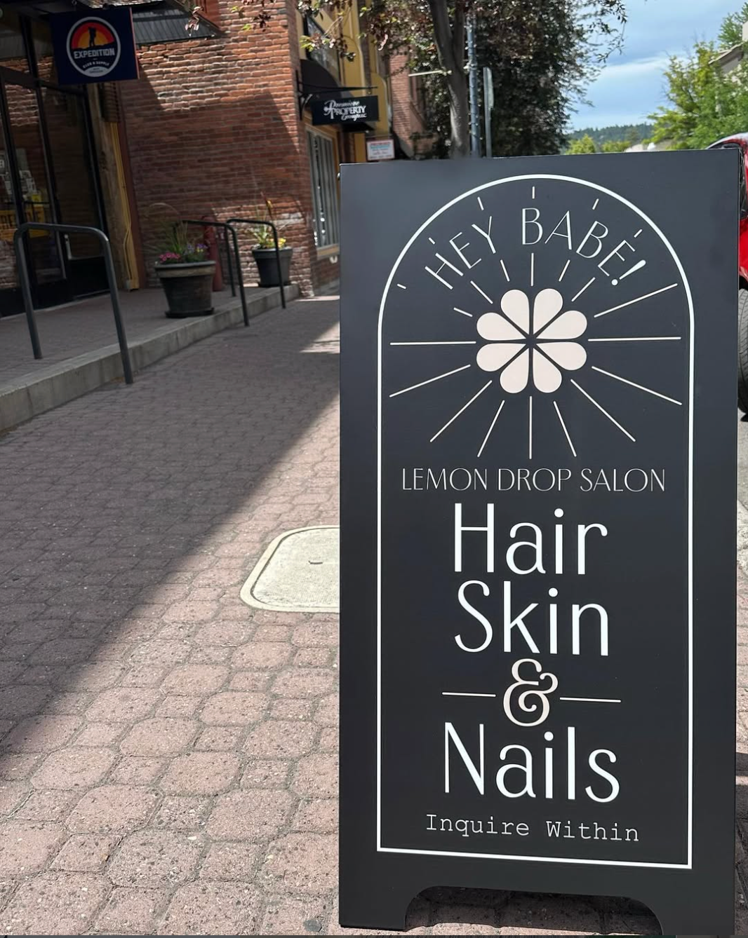 Outdoor sign for Lemon Drop Salon on a sidewalk