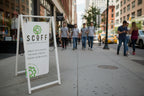 Outdoor sign for 'SCOFF' with eco-friendly branding on a sidewalk.